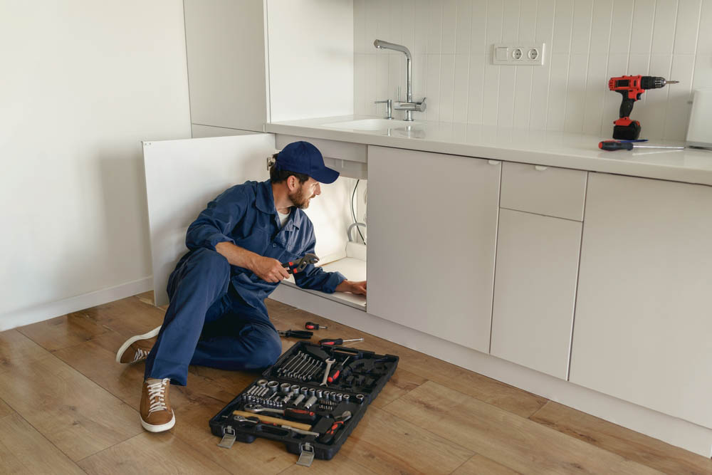 plumber inspecting pipes under sink